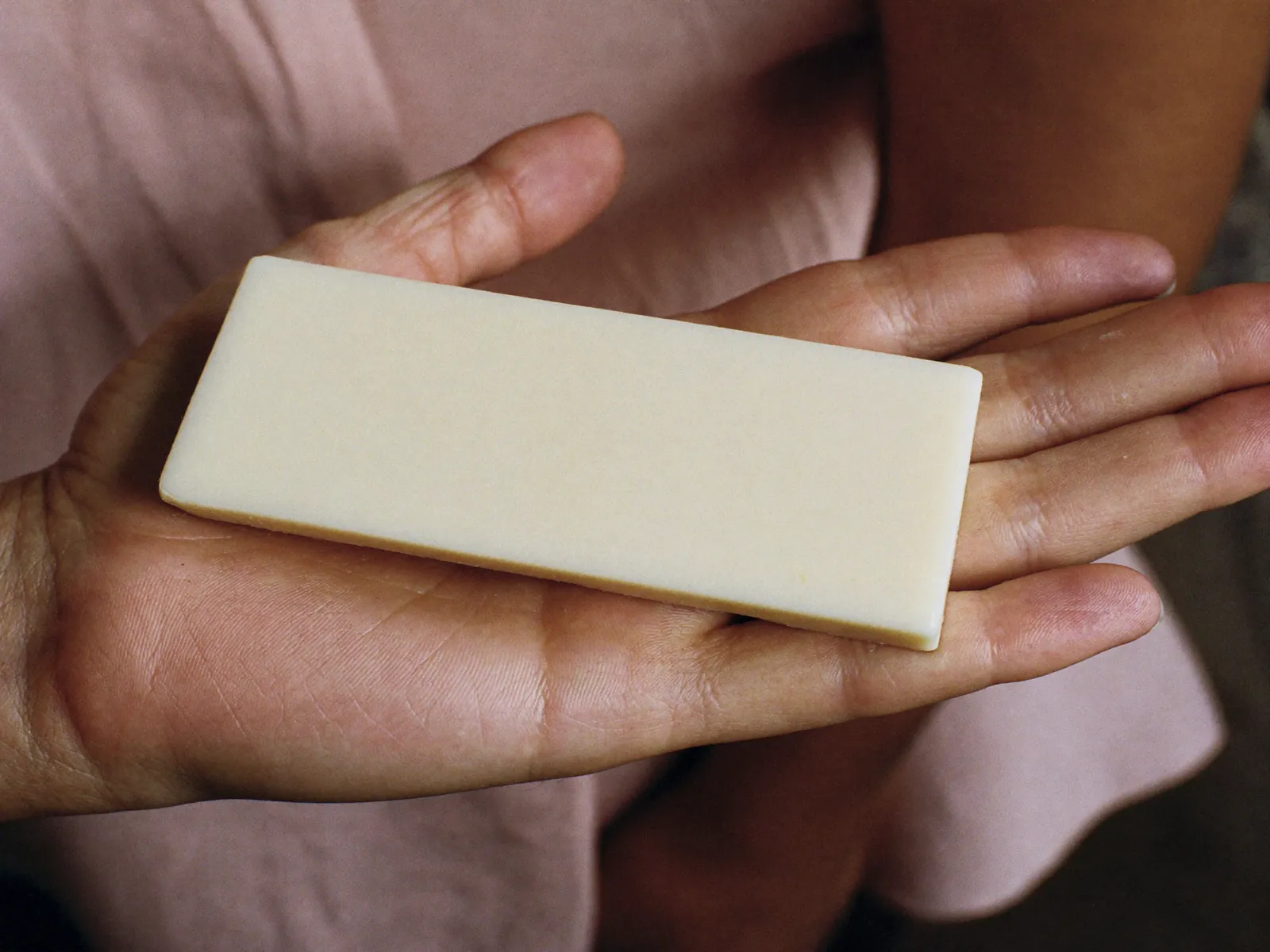 A pale cream rectangular bar resting across an adult’s open palm.